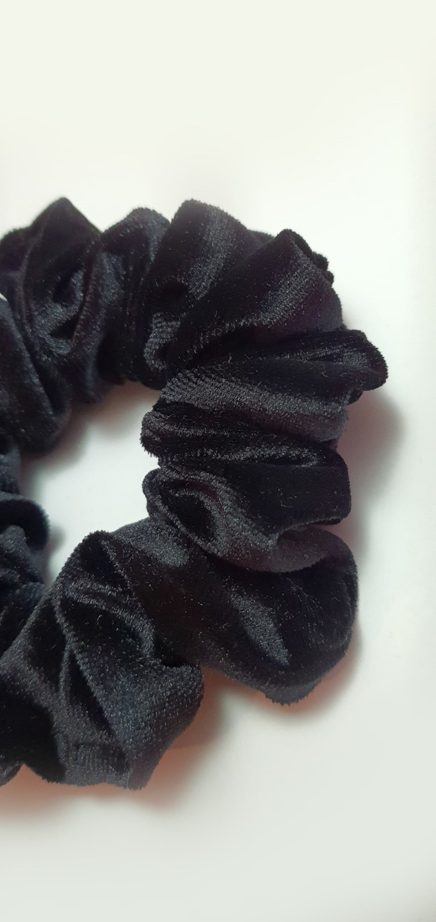 Classic black velvet scrunchie providing a soft, stylish hold for hair